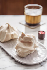 Homemade sweet meringue cookies and cup of coffee on white marble table. Delicious and light dessert. Selective focus