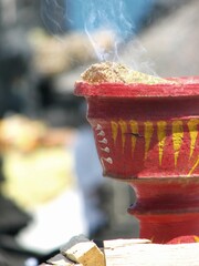 Close up of red pot incense burner with smoke in Balinese Hindu ritual event at a temple in Bali, Indonesia.