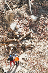 Obraz premium Two unidentified men inspect building demolition or explosion site, view from above.