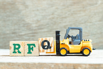 Toy forklift hold letter block Q to complete word RFQ (abbreviation of request for quotation) on wood background