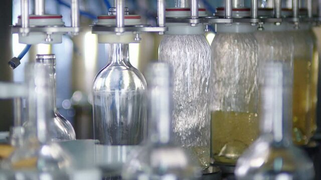 Wine production factory. Glass bottles filled up with white wine Bottling production line.
