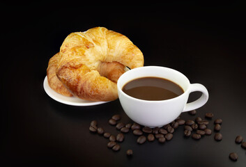 Croissants on a plate with a cup of espresso coffee and coffee beans on black background