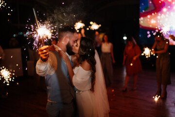 newlyweds with sparklers in night say goodbye to guests in the restaurant