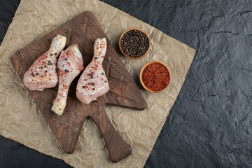 Top view raw chicken drumstick and spices on wooden board