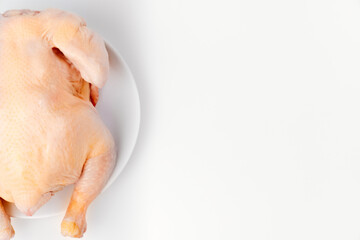 carcass of raw chicken on a white plate on a white background. 