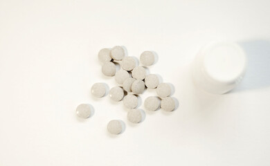 Scattered tablets and a jar of medicine close-up.
