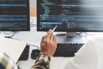 programmer writing program code with two monitors and working on a new software or hacker...