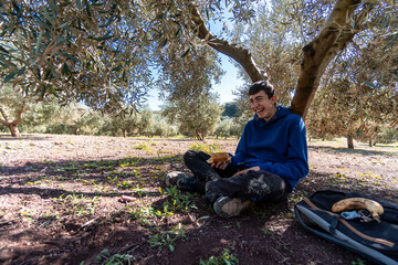 Young boy wearing sports clothes eating lunch and having fun while sitting in the countryside.