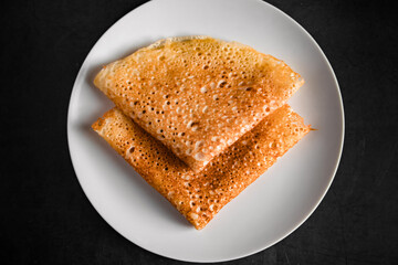 Tasty crepes on a plate on a black background. Traditional Russian food.