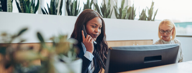Young African American businesswomen talking on an office telephone