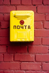 Vintage yellow letterbox from Soviet times on brown brick wall