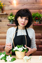 A worker in a black apron makes a beautiful bouquet of flowers and soap in a basket.