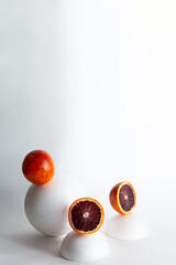 Creative still life with red orange fruits and white geometric shapes, spheres. Modern minimal composition with copy space