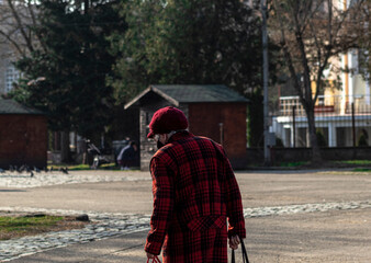 A grandmother dressed in red seen from behind in a park