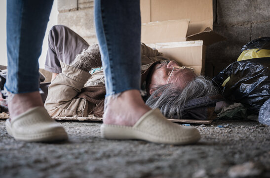 Senior homeless man and disabled lying on cardboard with help and food beggar because hungry from people on walking street.