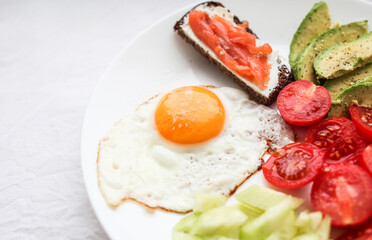 Breakfast - toasts, fried egg and vegetables, salmon, avocado