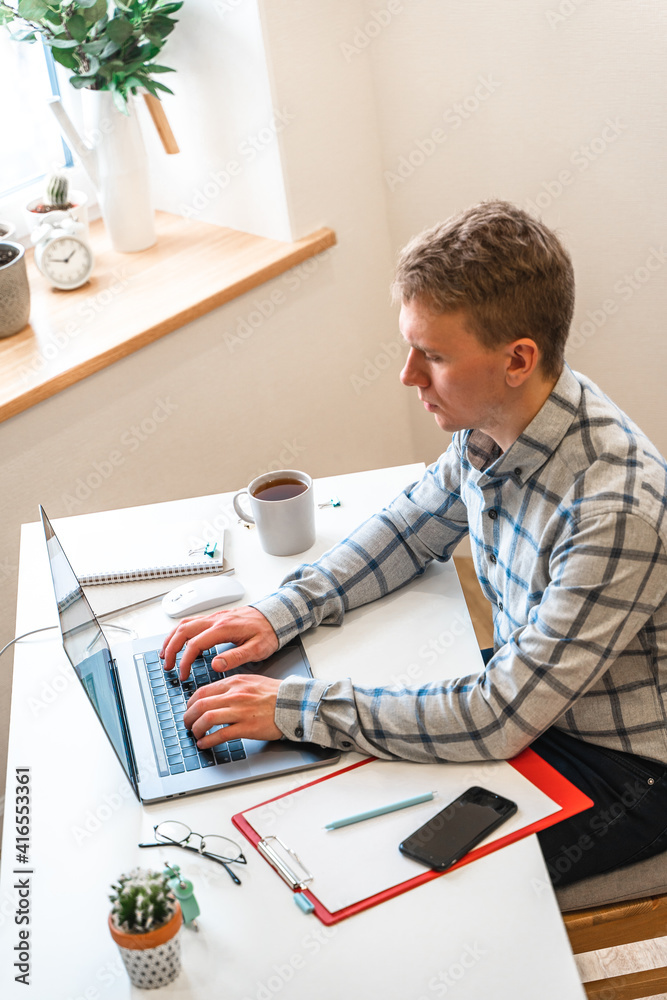 Canvas Prints a man in a shirt sits in a modern office and uses a laptop to work in business or programming, appli