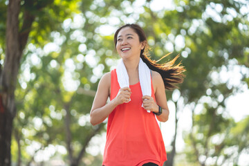 Close up of beautiful healthy Asian woman running and smiling in the park in the morning. Sports and health concept.