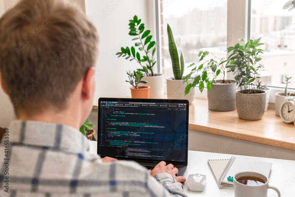 Canvas Prints a young male programmer uses a laptop and types code in the office. software, programming concept