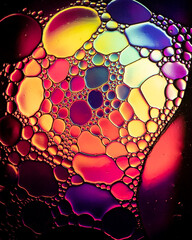 Oil drop bubbles on a water surface abstract with a bright orange and red background