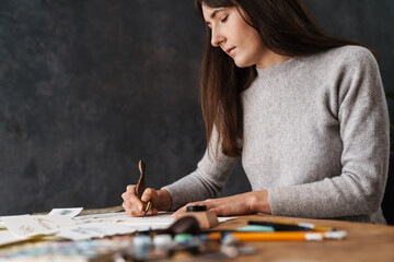 Serious beautiful calligrapher girl writing while working at table
