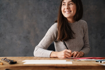 Smiling beautiful calligrapher girl writing while working at table