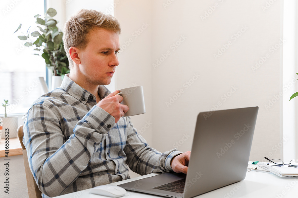 Canvas Prints handsome man working using computer laptop and drinking a mug of coffee with thinking serious face i