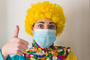 Linda mujer joven sonriendo mientras está vestida con un disfraz de payaso con una mascarilla...