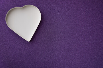 Obraz premium An empty white heart shaped box on a purple glittering background. 