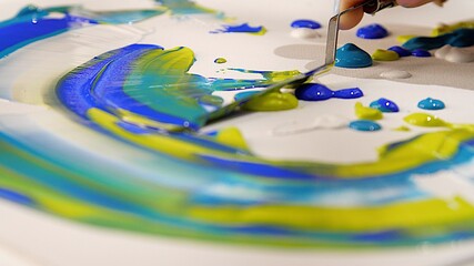 Drawing multicolored picture using metal palette knife. Large strokes of multi-colored paint....