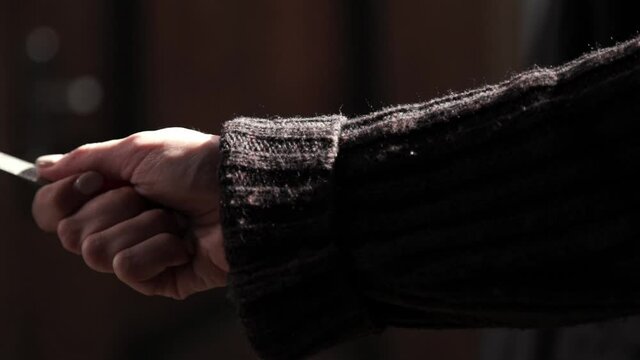 Human hand with knife shot on black background. Woman's hand in holds knife and strike.