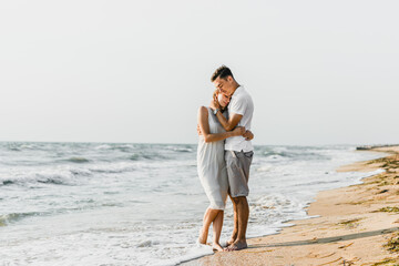 beautiful loving couple walks on the seashore. happy young couple spend time on the beach. honeymoon newlyweds. guy with girl at dawn of the day. couple on vacation. summer rest. couple hugging