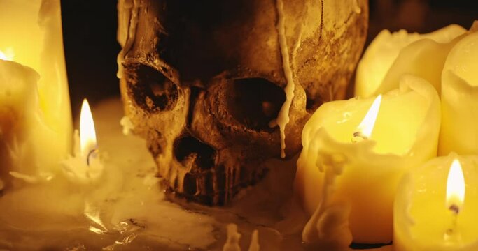 Candles and human skull in darkness closeup footage