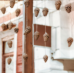 Christmas decoration made of pine cones hanging on a rope on the restaurant terrace. The idea of winter interior design.