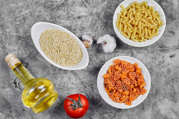 A bunch of different shaped uncooked pasta bowls on marble table