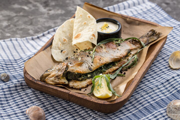 Grilled trout served with white sauce and flatbread on the table