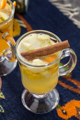 Apple tea with cinnamon stick in transparent cup on the table