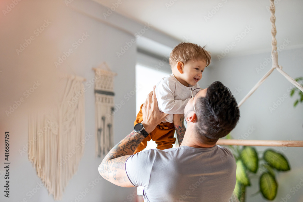 Wall mural father playing with his little son at home