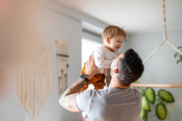Father playing with his little son at home
