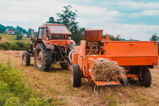 The process of harvesting hay for cattle, a tractor making bales in the field, old machinery.
