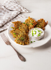 Potato pancakes or draniki with sour cream in plate on marble background