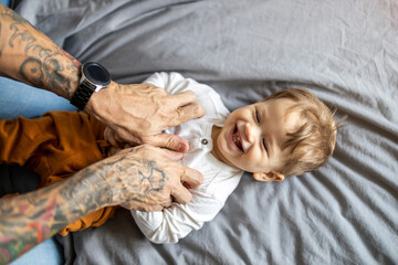 Father tickling his little son in bed
