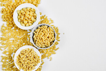 Various uncooked pasta bowls on white background