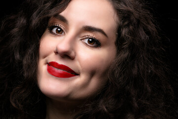 Portrait of a beautiful brunette girl with curly hair and red lipstick.