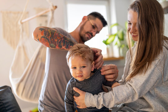 Young couple dressing their little son at home

