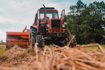 Old red tractor in the field, Ukrainian fields and old machinery, hay harvesting in the field.