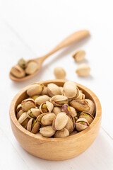 Pistachio nuts in a wooden bowl on white background