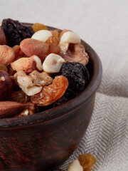 Close up at Mix nuts in wooden plate on wooden table background.Nuts including Cashew,walnuts,almonds, brazilian nuts,pecan and macadamia.Intake a handful of nut a day can stave off various disease.