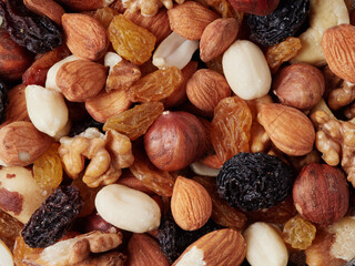 Close up at Mix nuts in wooden plate on wooden table background.Nuts including Cashew,walnuts,almonds, brazilian nuts,pecan and macadamia.Intake a handful of nut a day can stave off various disease.