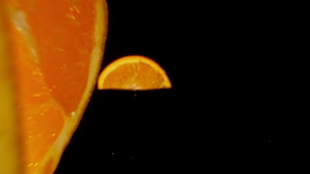 Fresh Orange Slices Falling on Black Background. Super Slow Motion, Wide Angle View.